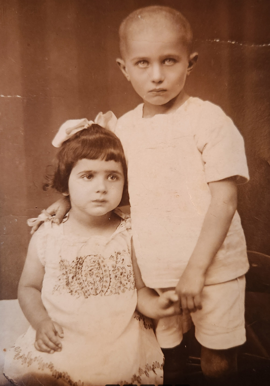 A vintage sepia photograph of two young siblings posing together