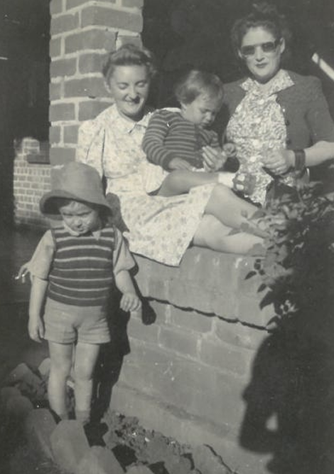 A vintage black-and-white photograph of two mothers with their young children
